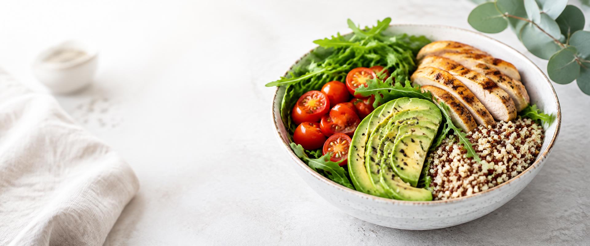 Healthy bowl with greens, tomatoes, avocado, grilled chicken and quinoa